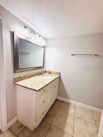 a bathroom with a granite countertop sink and a mirror