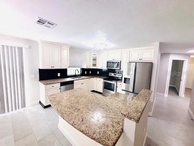 a kitchen with stainless steel appliances granite countertop a sink stove and refrigerator