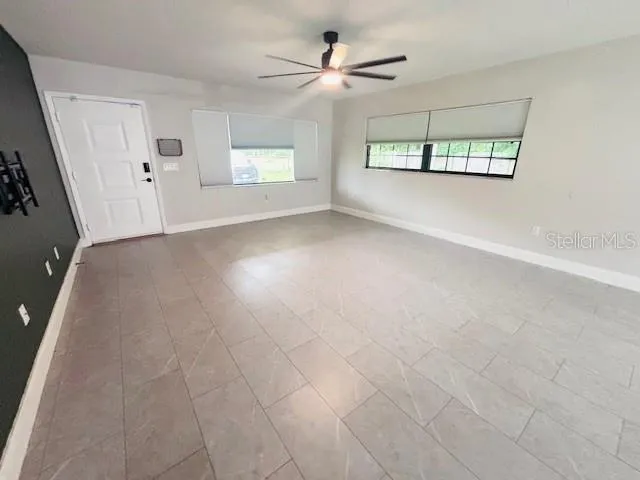 an empty room with windows and ceiling fan