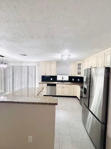 a kitchen with stainless steel appliances granite countertop a refrigerator sink and white cabinets
