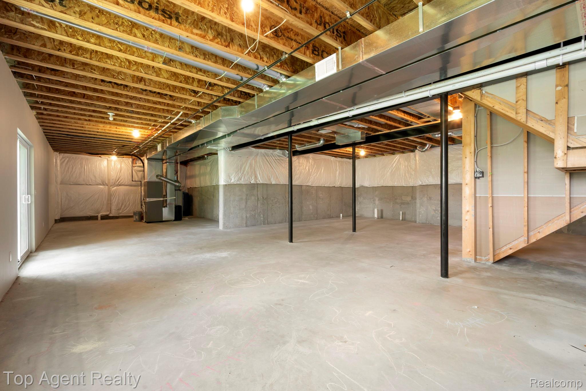 63770 Dequindre Road Washington, MI 48095 - Photo 46 of 61 Expansive unfinished lower level featuring exposed wood joists, concrete flooring, and an egress door