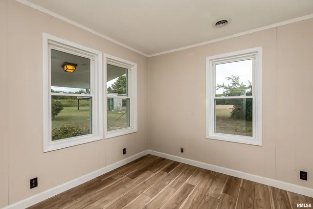 a view of an empty room with wooden floor and window