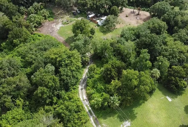an aerial view of residential houses with outdoor space and trees