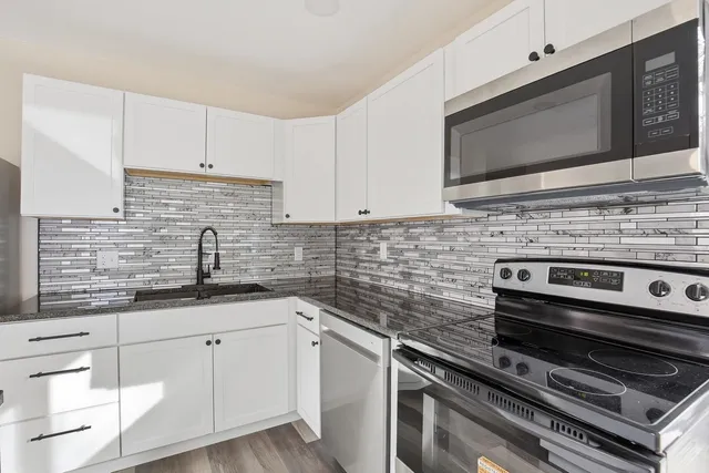 a kitchen with granite countertop a sink stainless steel appliances and cabinets