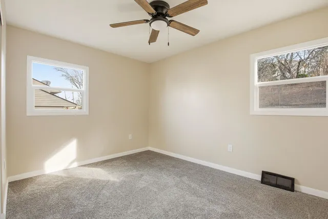 a view of an empty room with a window and a ceiling fan