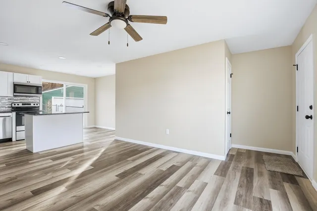 a view of kitchen and empty room with wooden floor
