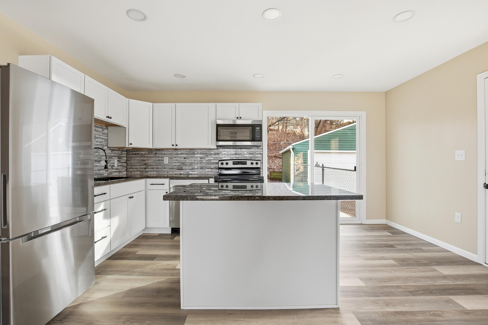 1135 6th Street West Milan, IL 61264 - Photo 7 of 36 a kitchen with stainless steel appliances granite countertop a refrigerator a stove top oven a sink and dishwasher with wooden floor