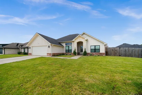 a view of a house with backyard and wooden fence