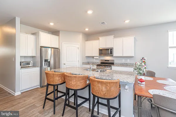 a kitchen with granite countertop kitchen island stainless steel appliances a dining table and chairs