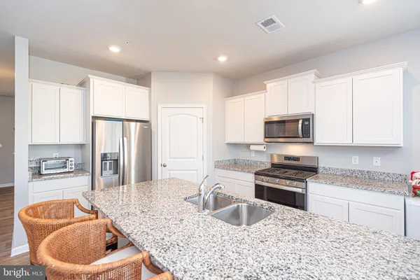 a kitchen with stainless steel appliances granite countertop a sink a stove and a refrigerator