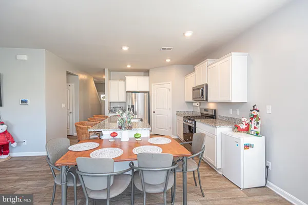 a kitchen with a dining table chairs refrigerator and microwave