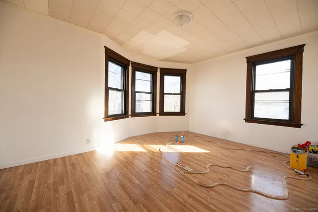 an empty room with wooden floor and windows