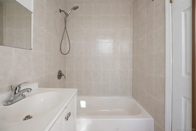 a bathroom with a white bath tub sitting next to a white sink and vanity