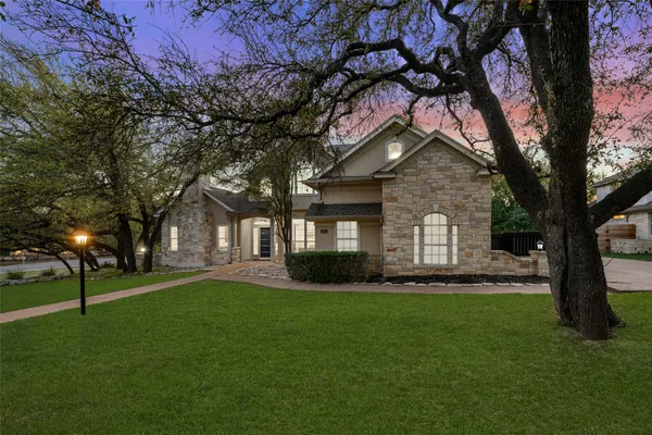 a front view of a house with a garden and trees