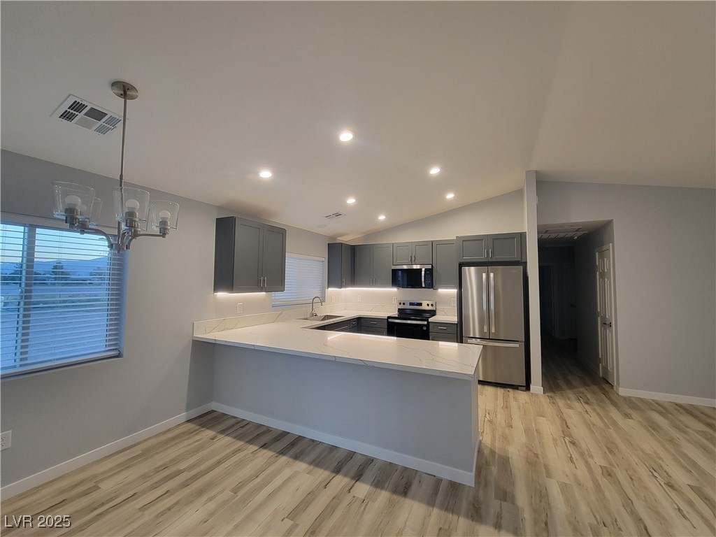 1021 East Manse Road Pahrump, NV 89048 - Photo 20 of 25 Kitchen featuring stainless steel appliances, gray cabinets, a peninsula, light wood finished floors, and lofted ceiling