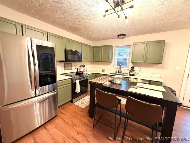 a kitchen with granite countertop a refrigerator stove top oven and sink