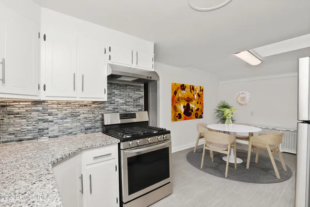 a kitchen with stainless steel appliances granite countertop a stove a sink and a white cabinets