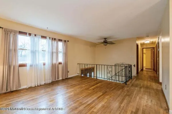 a view of a hallway with wooden floor and a bathroom