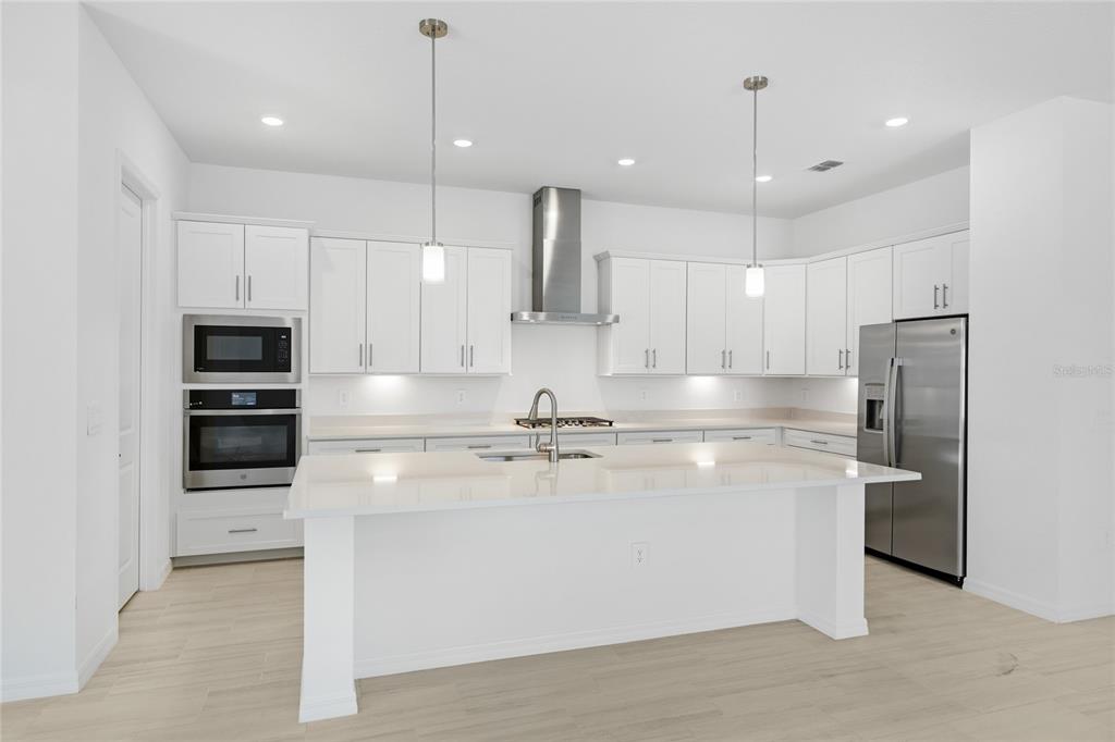 19156 Cherrystone Way Lakewood Ranch, FL 34211 - Photo 11 of 49 a kitchen with stainless steel appliances kitchen island a refrigerator and a stove top oven