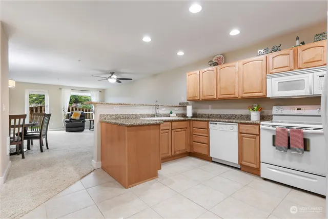 a kitchen with stainless steel appliances granite countertop a stove top oven a sink a dining table and chairs