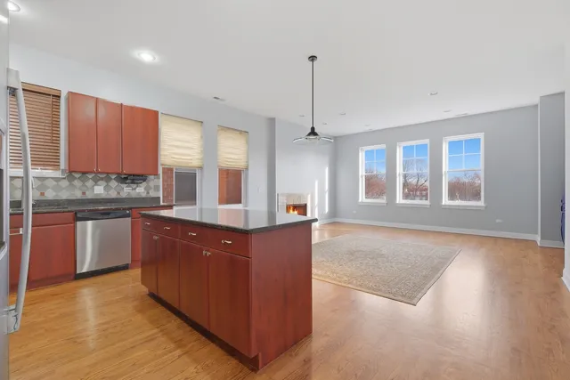 a kitchen with stainless steel appliances granite countertop a stove a sink dishwasher a refrigerator and a oven with wooden floor