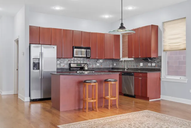 a kitchen with stainless steel appliances granite countertop a refrigerator a sink dishwasher a stove with wooden cabinets and floor