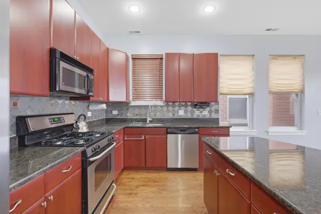 a kitchen with stainless steel appliances granite countertop a stove a sink and a refrigerator
