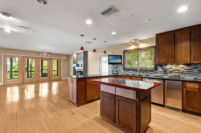 a kitchen with stainless steel appliances granite countertop a stove a sink dishwasher and a refrigerator with wooden floor