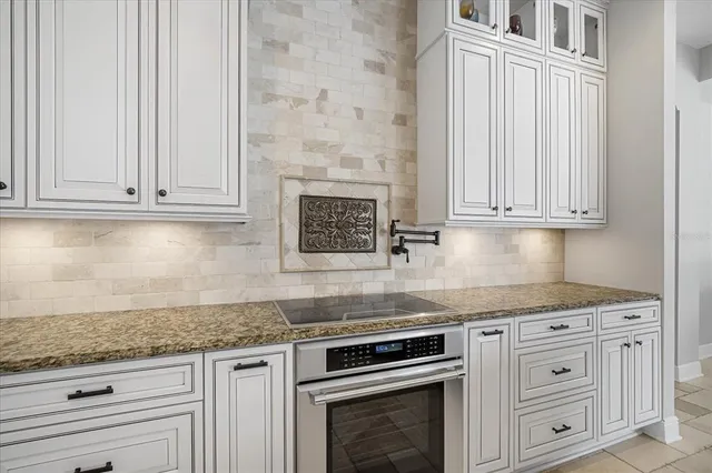 a kitchen with granite countertop white cabinets and a stove