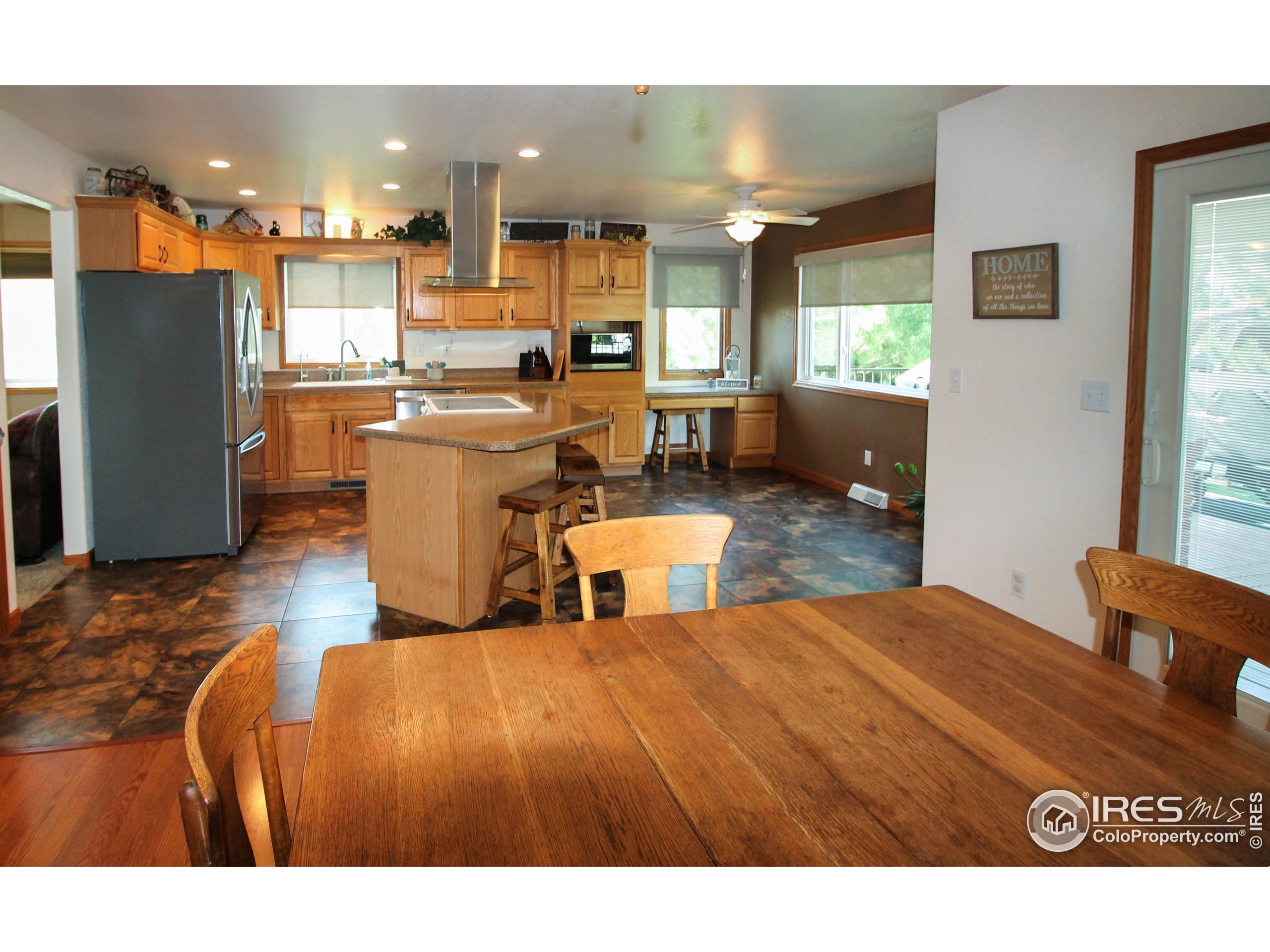 14363 Dakota Road Sterling, CO 80751 - Photo 9 of 40 a open kitchen with kitchen island a stove a sink dishwasher and a dining table with wooden floor