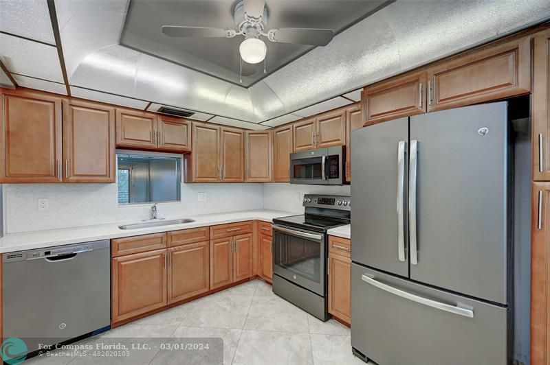 a kitchen with stainless steel appliances granite countertop a refrigerator a sink and white cabinets