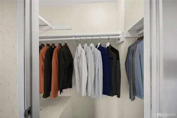 a view of walk in closet with clothes and shoes