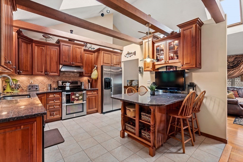 3 Macone Circle Stoneham, MA 02180 - Photo 8 of 26 a kitchen with stainless steel appliances kitchen island granite countertop a table chairs and a refrigerator