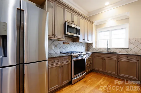 a kitchen with stainless steel appliances granite countertop a refrigerator stove a sink and a microwave