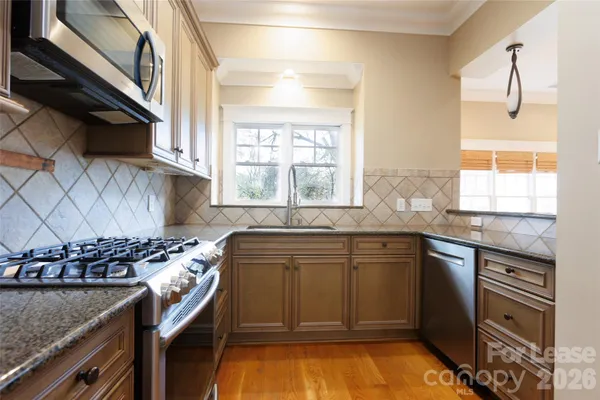 a kitchen with stainless steel appliances granite countertop a sink stove and cabinets