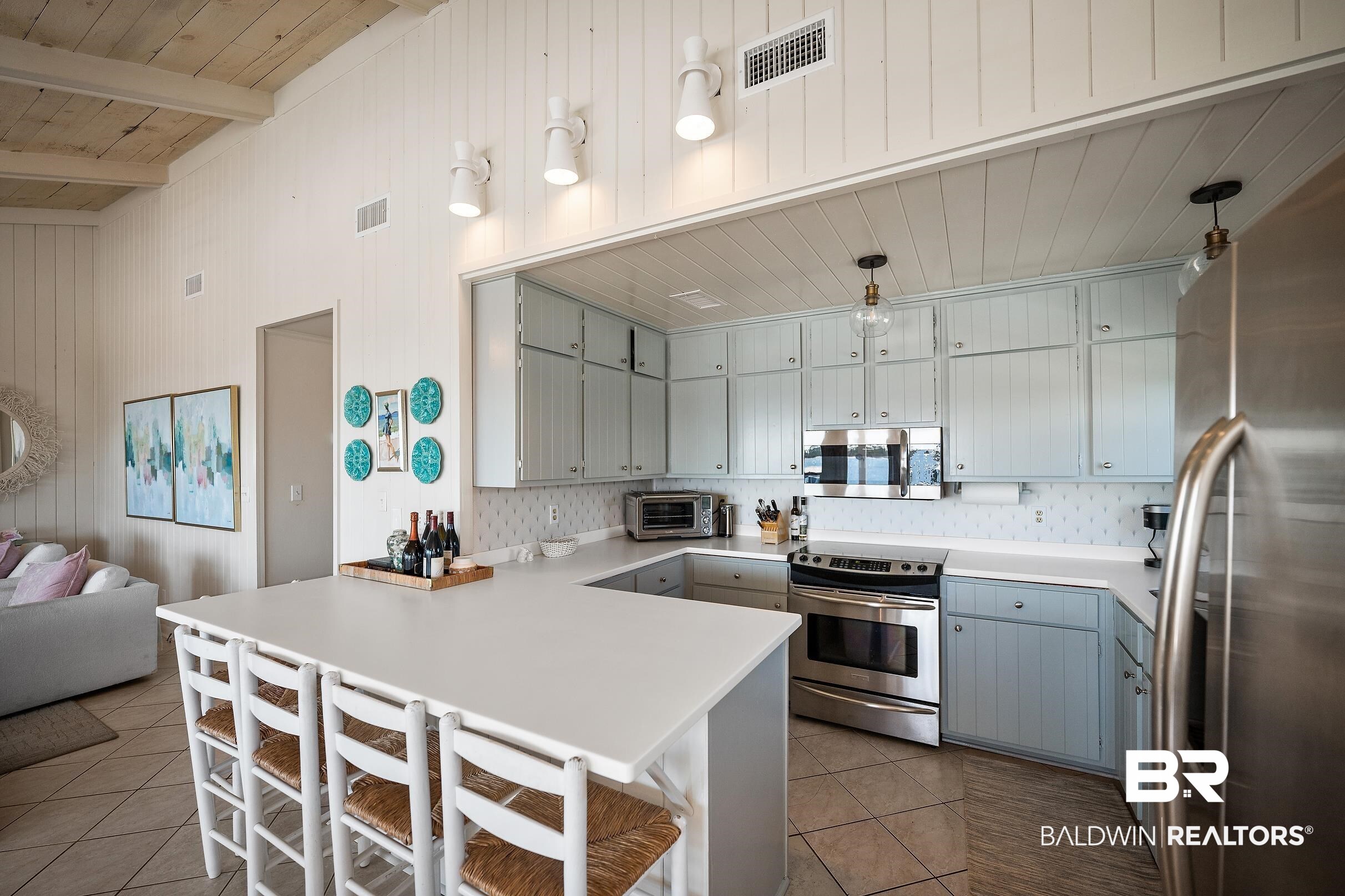 32620 River Road Orange Beach, AL 36561 - Photo 15 of 60 Kitchen with gray cabinets, a breakfast bar, stainless steel appliances, a peninsula, and a high wooden beamed ceiling