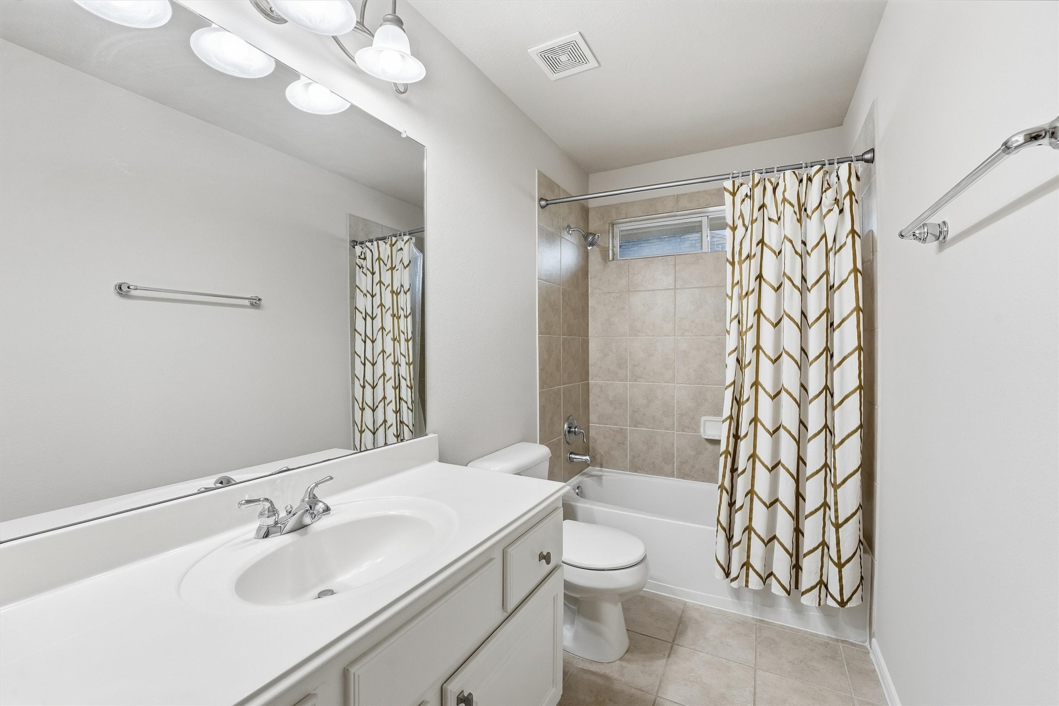 17415 Memorial Mills Drive Spring, TX 77379 - Photo 26 of 37 Upstairs en-suite bathroom featuring a single vanity with ample counter space, oversized wall mirror, and a tub/shower combination with tile surround. Neutral finishes, overhead lighting, and a window provide a bright, clean feel.