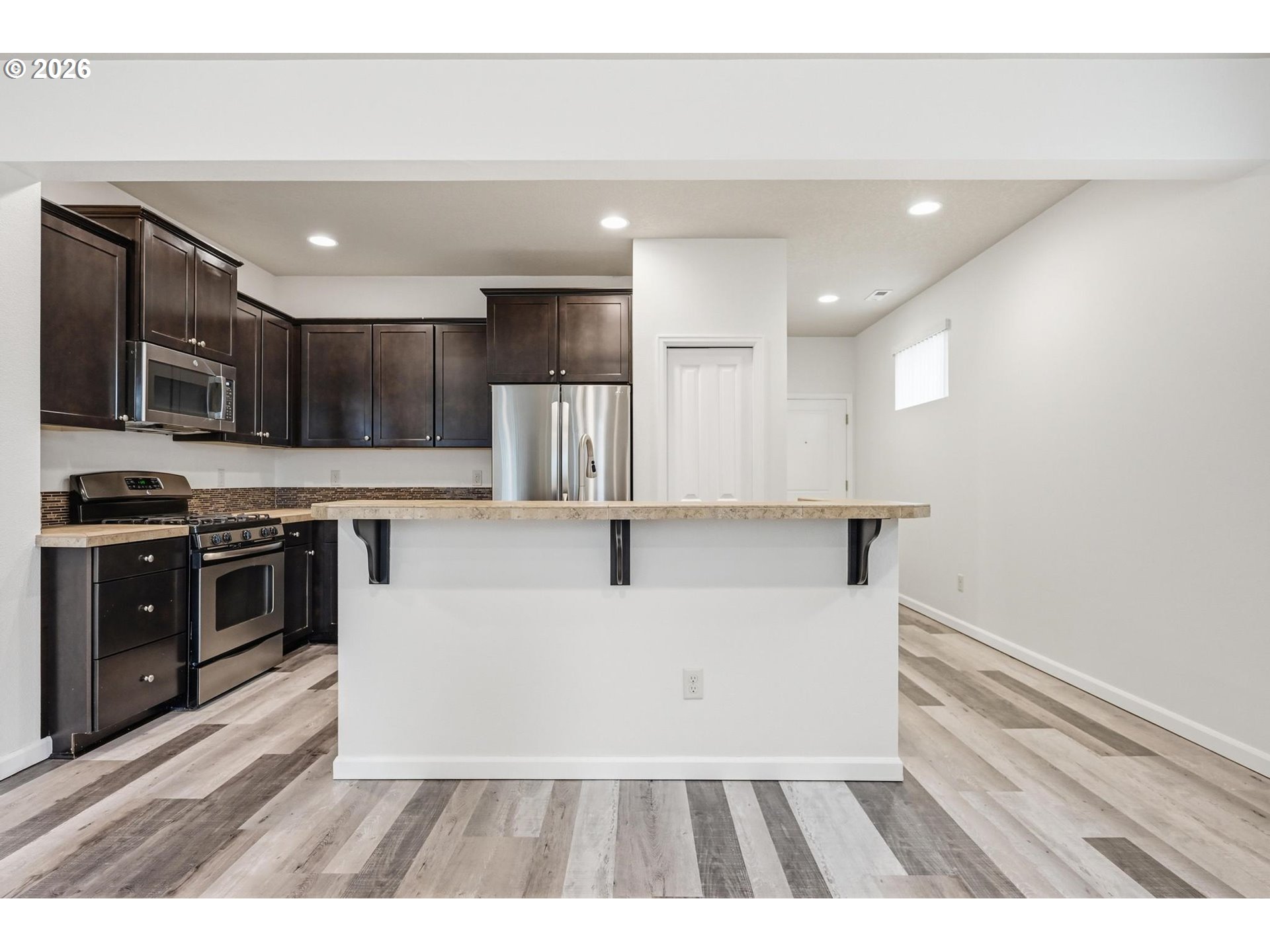 20881 Southwest Edgemont Street Beaverton, OR 97003 - Photo 7 of 39 a view of a kitchen with kitchen island a sink stainless steel appliances and cabinets