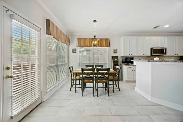 a kitchen with kitchen island a dining table chairs and a refrigerator