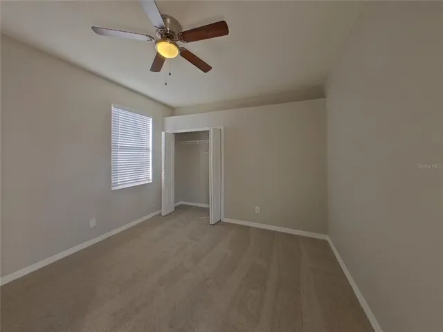 an empty room with ceiling fan and window