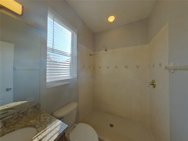 a bathroom with a granite countertop toilet a sink and shower