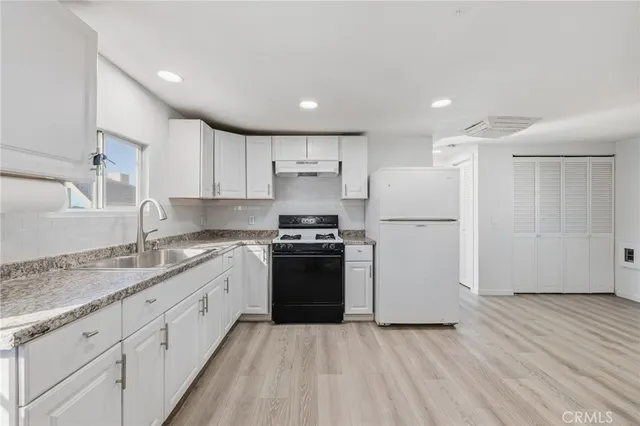 a kitchen with granite countertop a sink stove and refrigerator