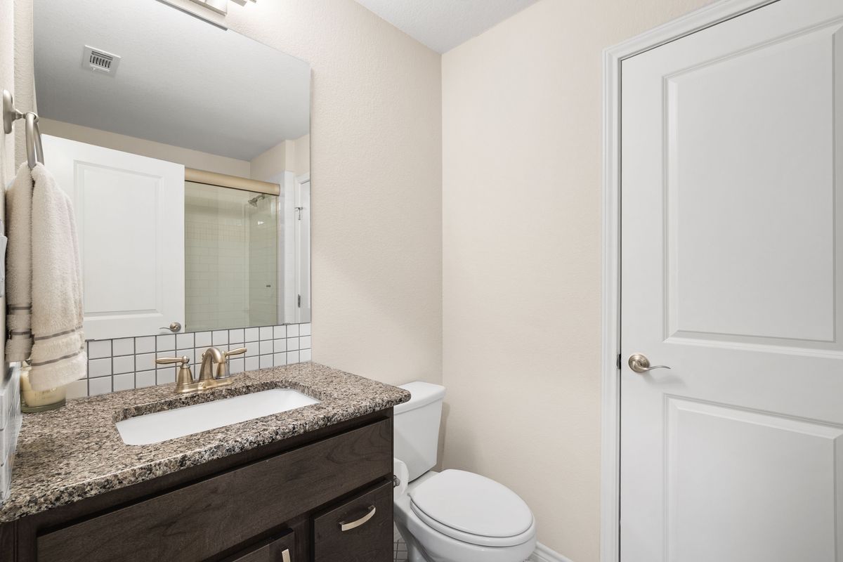 1116 Highknoll Lane Georgetown, TX 78628 - Photo 33 of 36 a bathroom with a granite countertop sink a toilet and a mirror