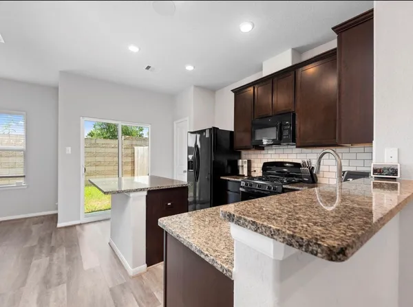 a kitchen with kitchen island granite countertop stainless steel appliances stove microwave refrigerator sink and cabinets