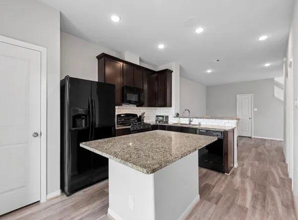a kitchen with kitchen island granite countertop stainless steel appliances a sink and refrigerator