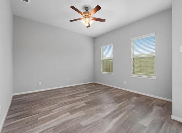 an empty room with wooden floor and windows