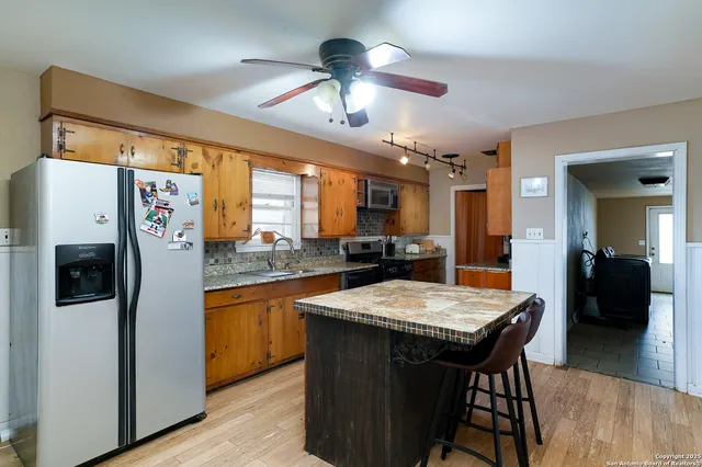 a kitchen with stainless steel appliances granite countertop a table chairs stove and refrigerator
