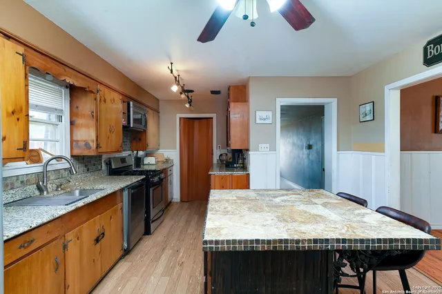 a large kitchen with kitchen island a counter space a sink stainless steel appliances and cabinets