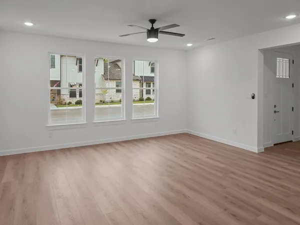 an empty room with wooden floor and windows