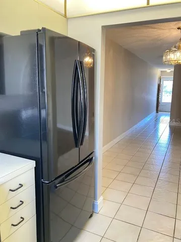 a view of a refrigerator in kitchen and an empty room